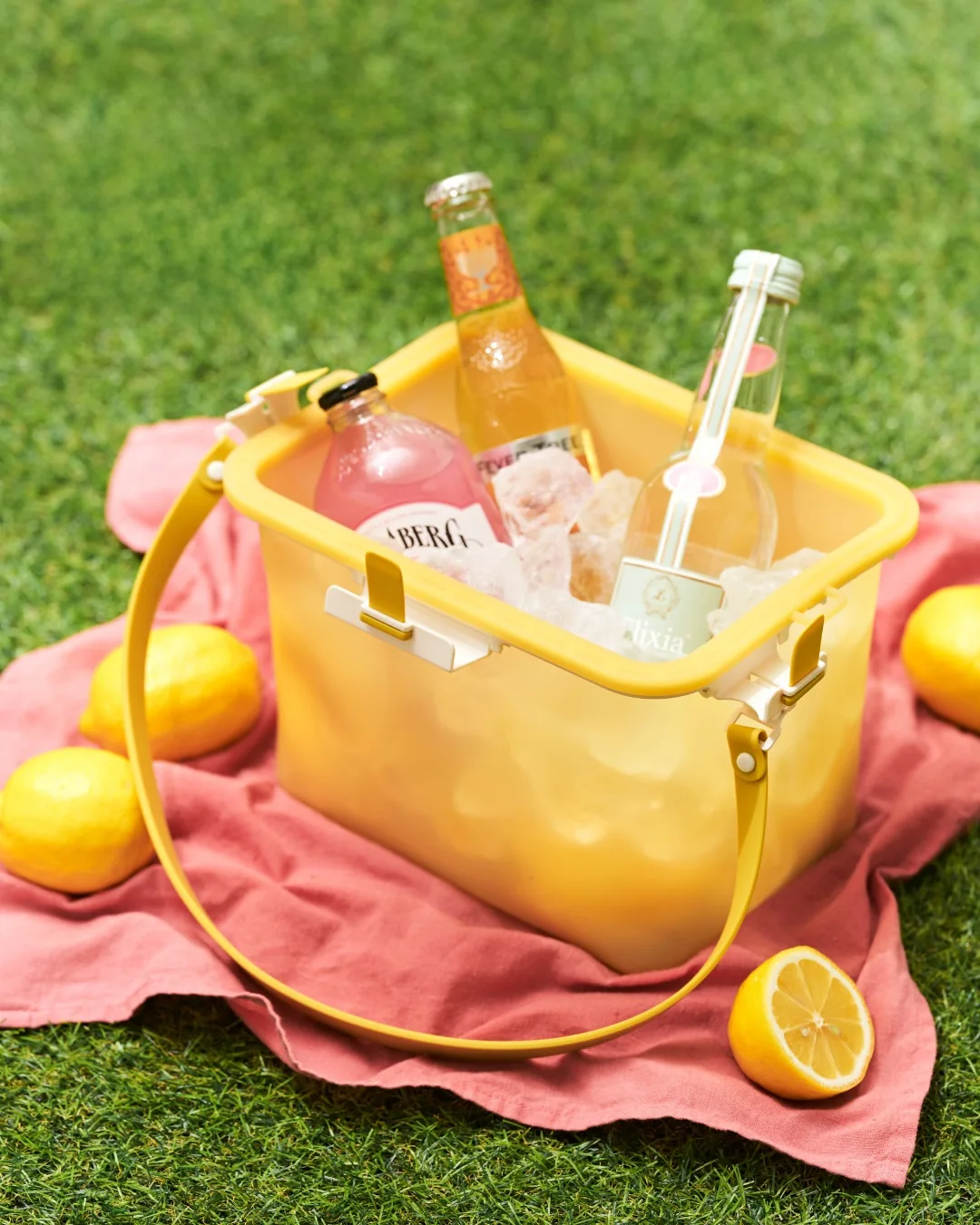 Yellow silicone bag holding picnic items on a checked blanket