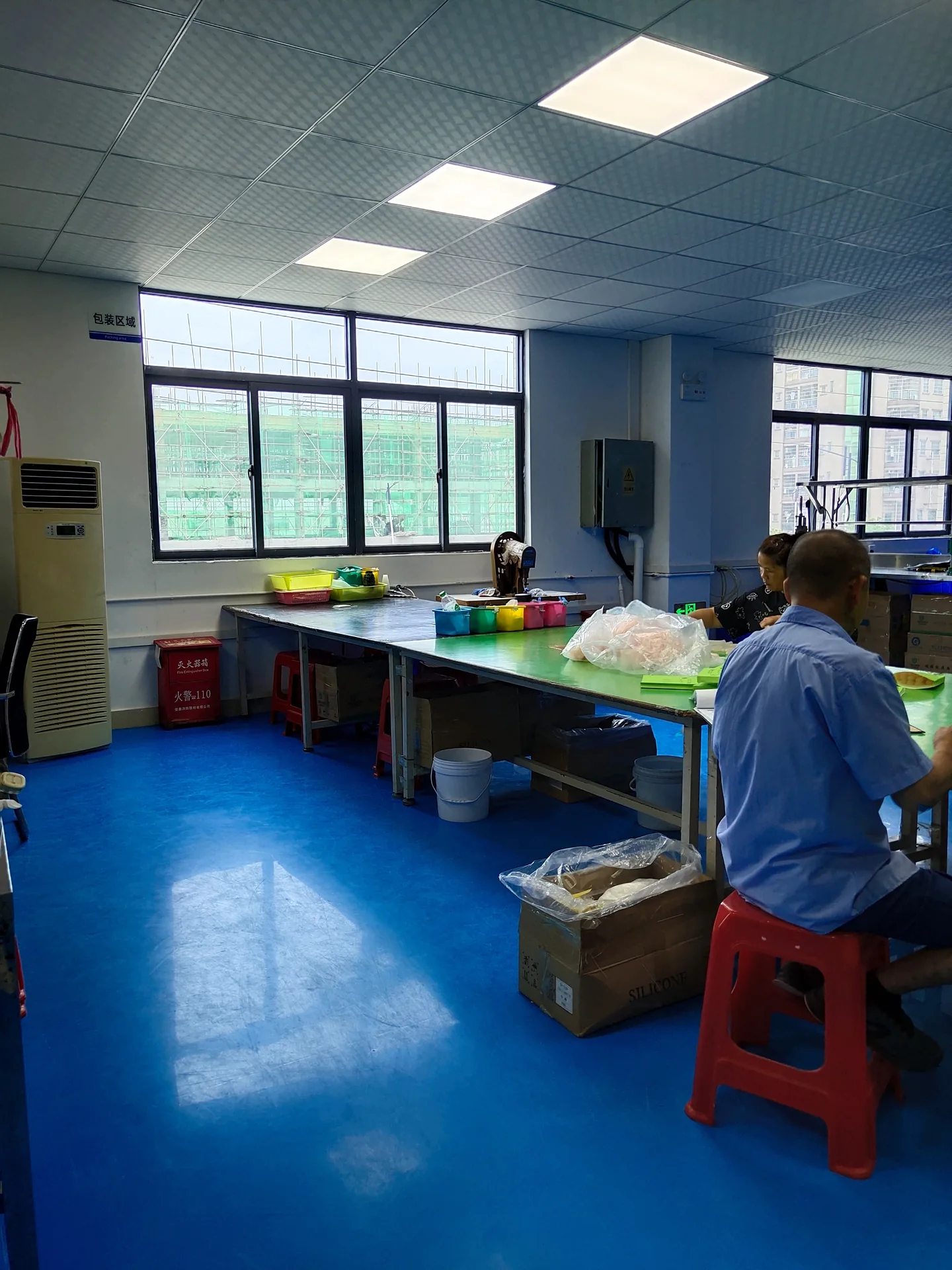 Packing workroom with blue flooring and staff at worktables