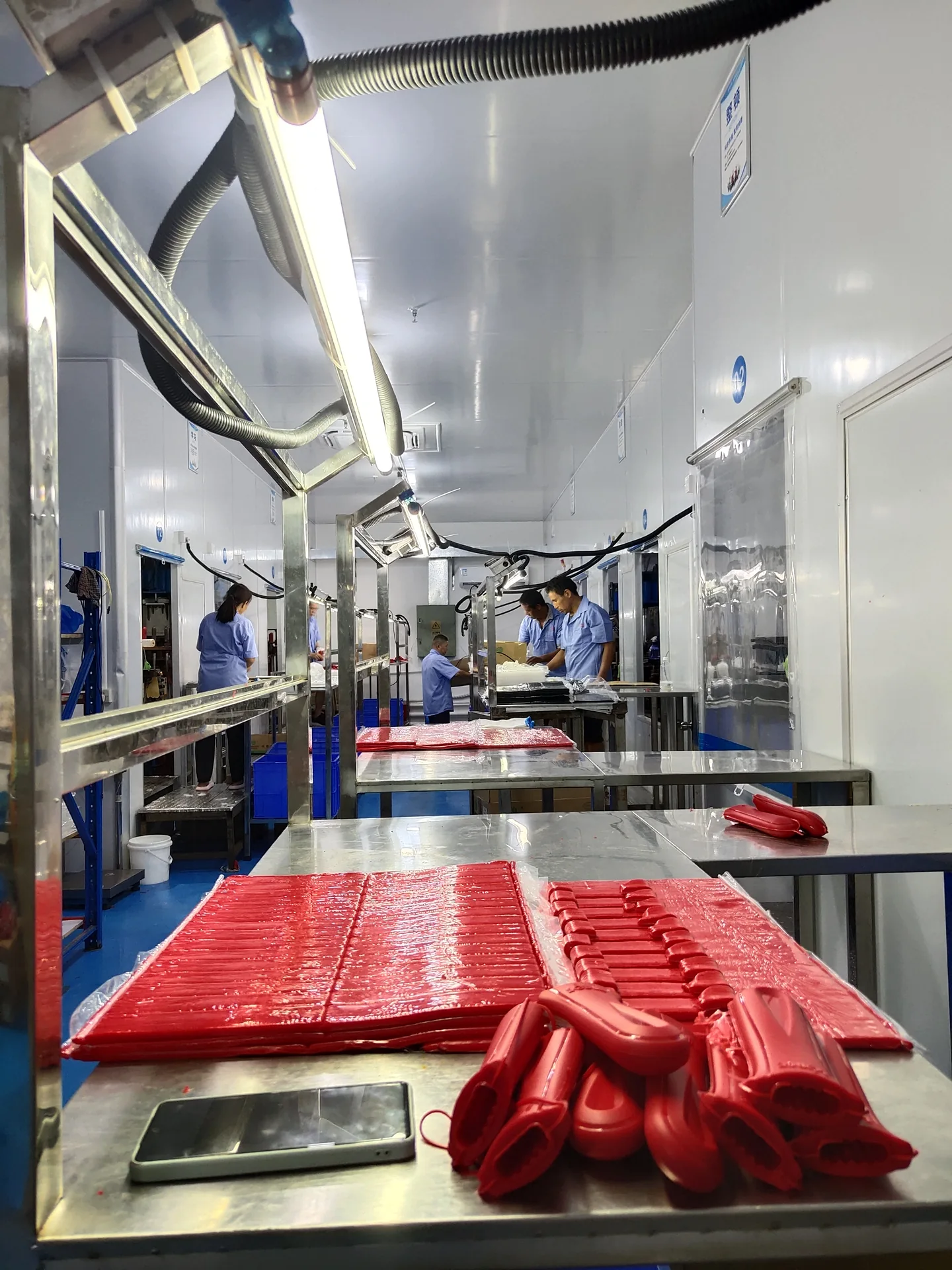 Red silicone components on a workbench beneath molding equipment